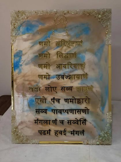 The final look of a student's handmade Navkar Mantra frame. The combination of earthy tones, sky blue, and sparkling crystals gives it a very calming and natural feel.