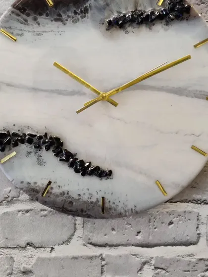 This mesmerizing 14 inch resin clock features a black, grey, and golden design with embedded black stones. It's a unique timepiece designed to add a stylish touch to your living room or office.