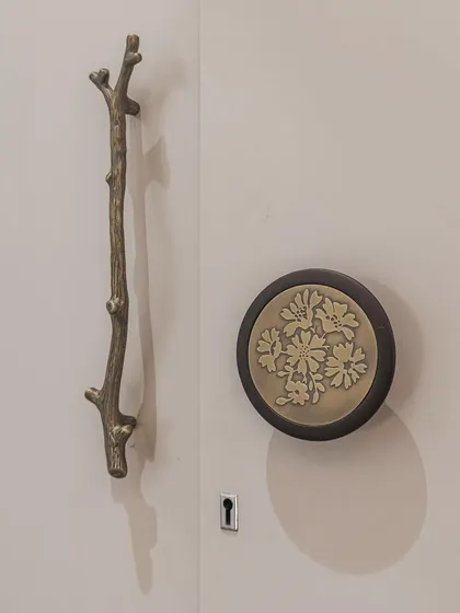 A close-up of the unique hardware selected for our "Mother of Pearl" wardrobe. The branch-like handle and floral-embossed knob are artistic details that elevate the entire piece.