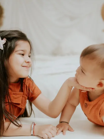 A gentle touch from a loving big sister. This photo beautifully captures their sweet and caring bond.