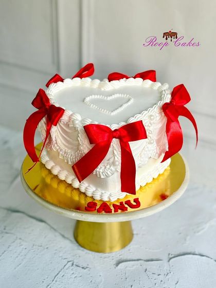 Elegance in simplicity. This vintage-style heart-shaped cake is adorned with delicate piping and beautiful red ribbons.