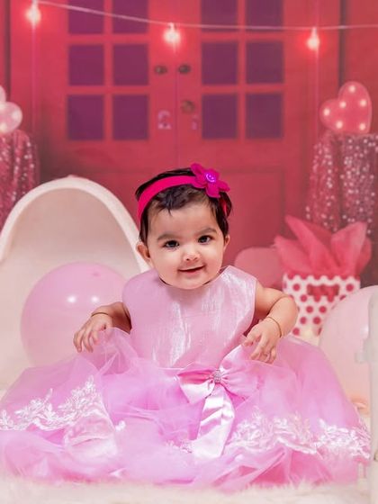 A vibrant, all-pink Barbie-themed first birthday shoot. The dollhouse backdrop and matching accessories create a fun and playful atmosphere for the birthday girl.