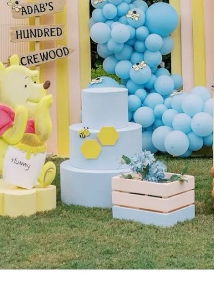 A life-sized Pooh Bear prop with his 'hunny' pot, sitting next to a themed cake. This is a central piece of our Hundred Acre Wood setup.