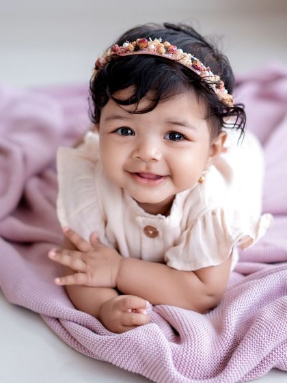 A beautiful sitter session portrait. This baby girl's sweet smile and bright eyes are captivating.