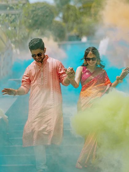 A dynamic shot of the couple walking through clouds of colored smoke, adding a touch of modern fun to their Haldi celebration.