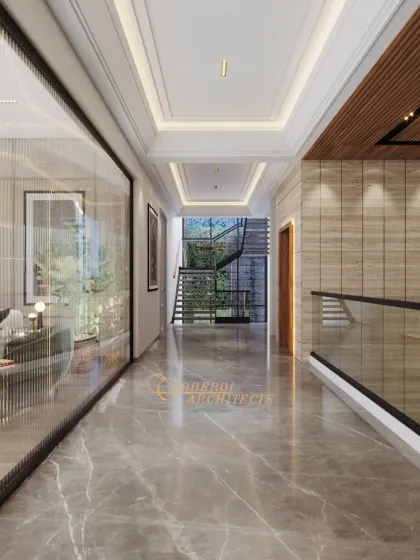A hallway that balances different materials beautifully, with a glass partition offering a glimpse into the living room, a textured stone wall, and a view of the staircase beyond.