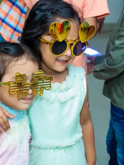 Two young friends sharing a fun moment with heart shaped and clover shaped novelty glasses. These props are great for cute, memorable photos.