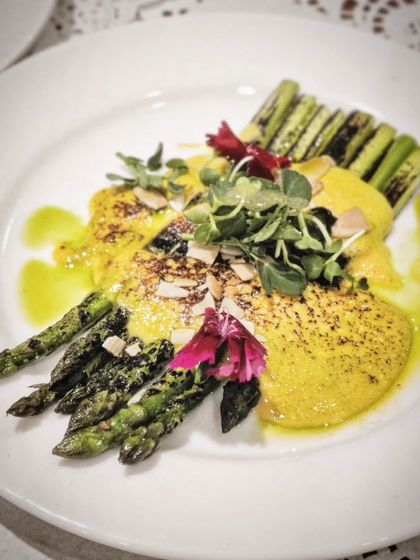 A celebration of spring on a plate. This dish features charred asparagus with a rich Coleman's hollandaise, toasted almonds, and a drizzle of herb oil.