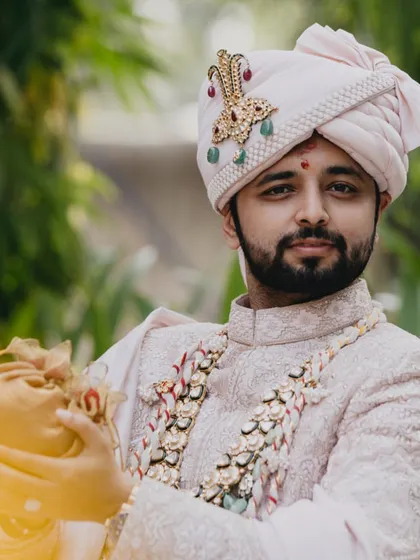 A portrait of the handsome groom, ready for his wedding, holding the traditional 'shreefal'.