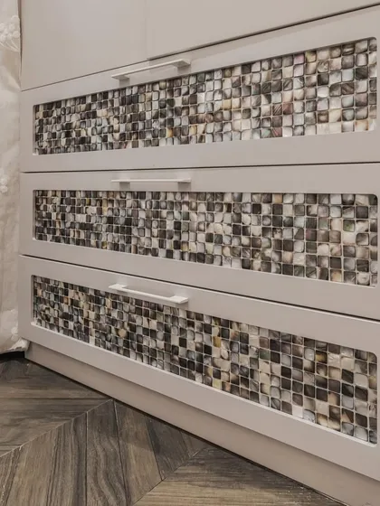 A close-up of the stunning mother of pearl tile drawers. This unique, exquisite touch elevates the wardrobe from a simple storage unit to a piece of decorative art.