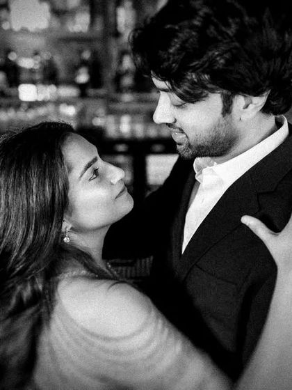 An intimate black and white close-up taken during a bar photoshoot. The low light and intense gaze between the couple create a moody and romantic atmosphere.