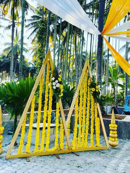 For this haldi setup, I used modern triangular wooden frames decorated with strings of yellow marigolds. This design combines contemporary geometric shapes with traditional flowers for a unique look.