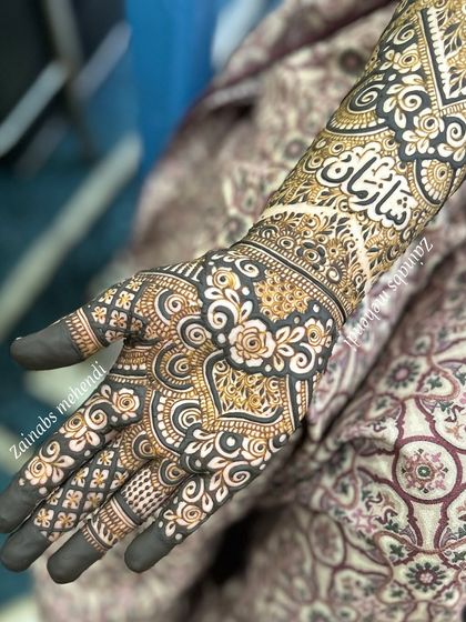 A close-up of the groom's name, 'Shahan', written in elegant Urdu calligraphy on bride Tasmiya's arm.