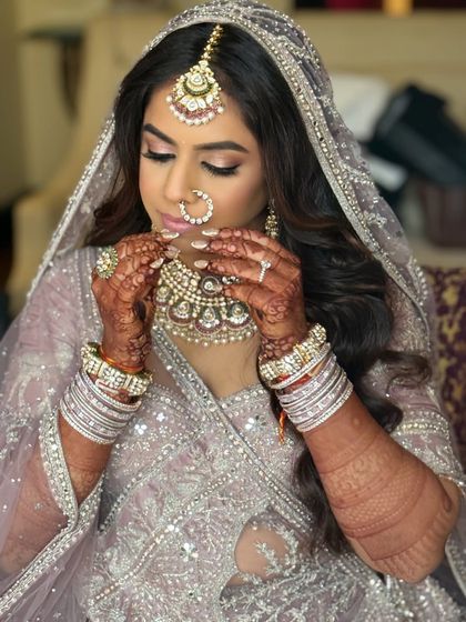 A close-up of the bride adjusting her jewelry. The soft waves in her hair and the delicate makeup create a romantic look.