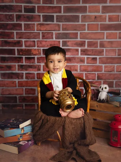 This little wizard is ready to cast a spell. The brick backdrop and prop books help create an authentic Hogwarts feel right in the studio.