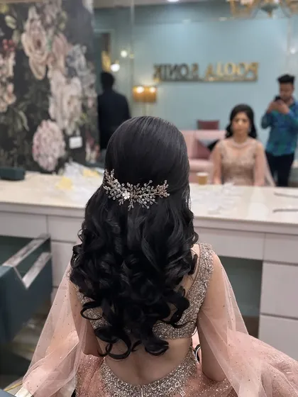 A beautiful engagement hairstyle with tight curls and a sparkling accessory, seen from the salon chair.