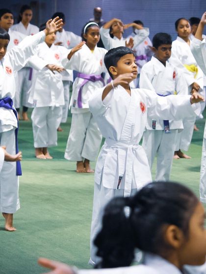 Young students in white and purple belts practice their stances during a group training session before their grading exam. We focus on perfecting the basics to build a strong foundation.
