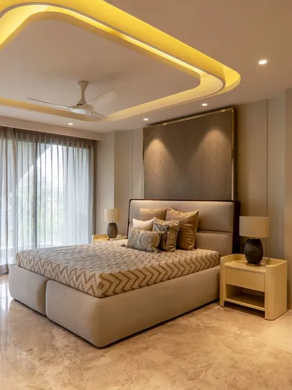 This bedroom features a unique curved ceiling with integrated cove lighting, creating a soft, ambient glow. The design uses a minimalist approach with earthy tones to craft a tranquil and modern retreat.