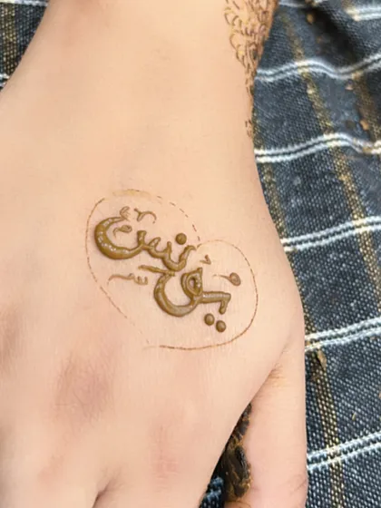 A close-up of the groom's name, "Yunus," written inside a heart on the palm. It’s a sweet and romantic touch.