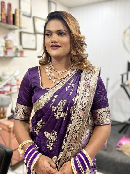 A beautiful client ready for a party. Her hair is styled with soft, glamorous waves and highlights, a perfect look for a modern saree.