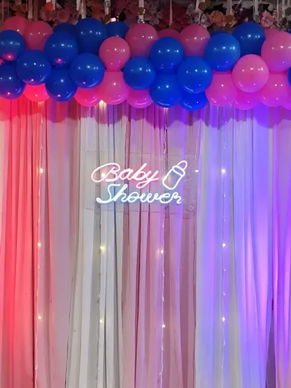 A close-up of the "Baby Shower" neon sign against an elegant curtain backdrop.