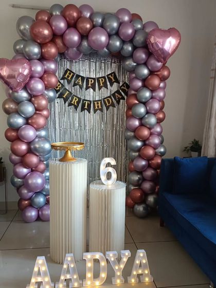 A stylish 6th birthday home decoration with a metallic balloon arch in rose gold, silver, and lavender.