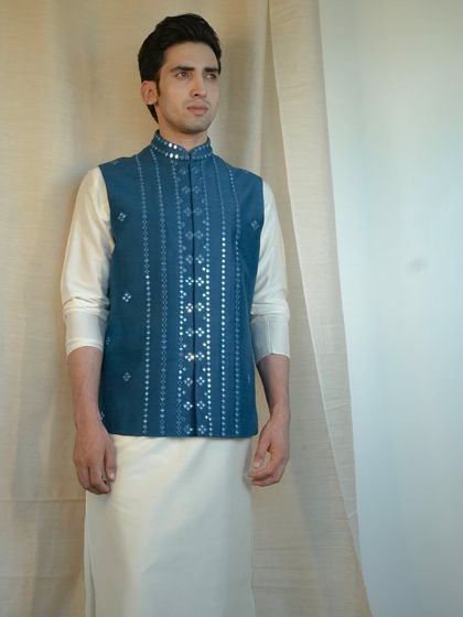 The fancy mirror work on this blue jacket pairs beautifully with a stylish silk kurta, creating a look of resplendent royalty.