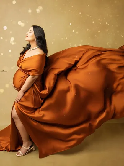This dramatic solo portrait showcases our flying fabric technique. The rich, rust-colored gown billows out, creating a sense of movement and grace against a warm, glowing backdrop.