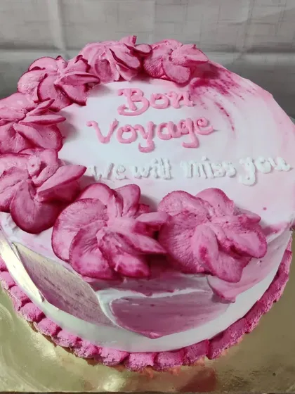 A "Bon Voyage" farewell cake. The pink floral design and heartfelt message make for a sweet send-off.