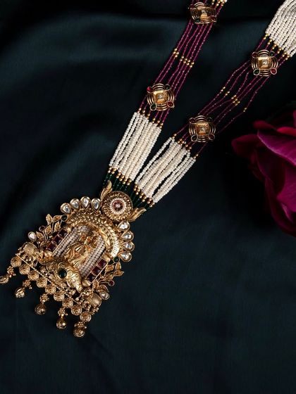 An artistic close-up of the temple jewellery necklace against a dark background with a single rose, adding a touch of romance and elegance.