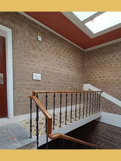 A staircase with exposed soil cement block walls, lit by a skylight, creating a bright and textured passageway.