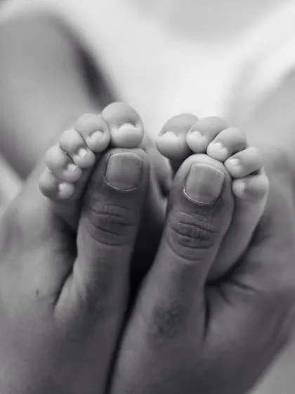 A classic black and white shot of a parent's hands holding their baby's tiny feet. This timeless image is a must-have for any newborn session.