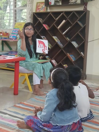 The storyteller shows an illustration of a red animal, prompting a discussion about colors and imagination.