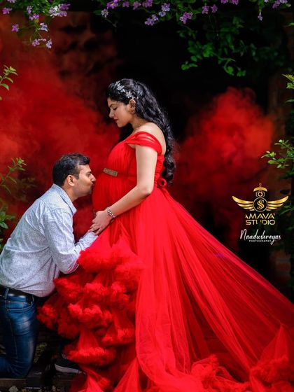 A dramatic and romantic shot using red smoke for effect. The partner's gentle kiss on the baby bump makes this a powerful and memorable outdoor maternity photo.