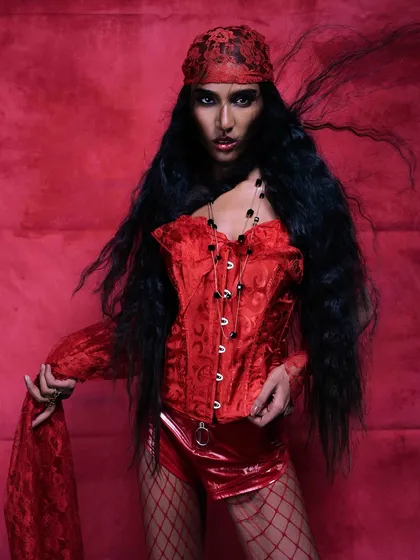 A full-look shot from the 'Crimson Whispers' editorial, capturing a powerful stance with dramatic hair movement and a monochromatic red theme.