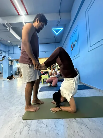 Safe, hands-on adjustments are a key part of learning. Here, I'm helping a student find stability and alignment in her headstand (Sirsasana), ensuring her foundation is strong and secure. This is a core skill we focus on in the teacher training course.