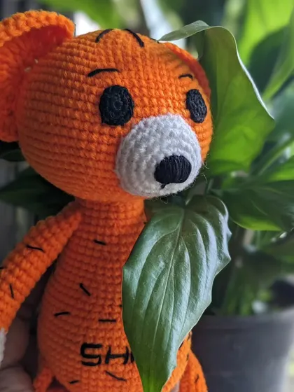 The tiger doll peeking from behind a leaf.