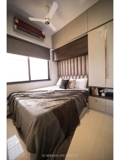 This compact parent's bedroom is designed for maximum comfort and storage. The upholstered headboard extends to the ceiling, and the wardrobe provides ample space, all in a soothing, neutral palette.