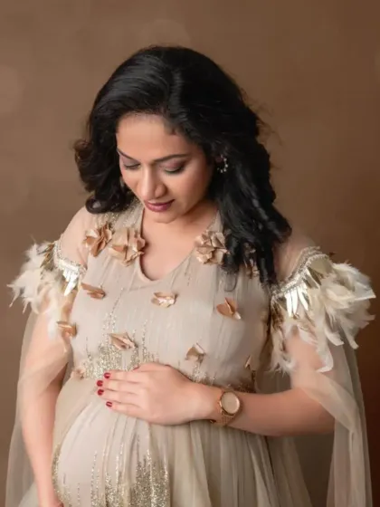 A close-up portrait in our beige gown with delicate feather and floral shoulder details, showcasing its unique and elegant design.