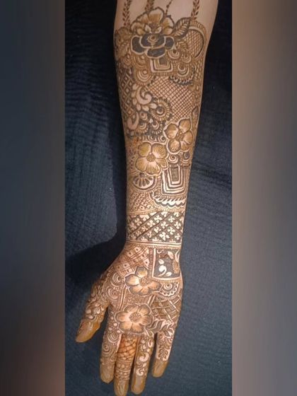 This image showcases a full-arm bridal design with beautiful shading and detail. The central floral elements are surrounded by delicate net and leaf patterns.