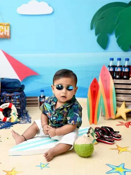 Too cool for the pool! This little guy is ready to hit the waves in our fun beach-themed setup, complete with a surfboard, sunglasses, and a refreshing coconut drink.