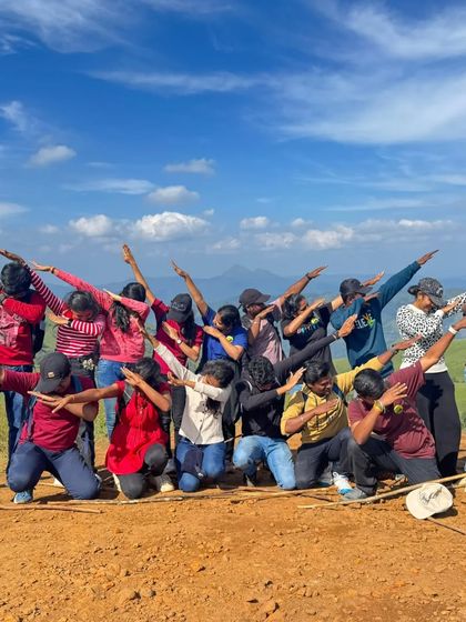 The classic "dab" pose from a fun-loving group against a backdrop of blue skies and green hills. We never forget to have fun.