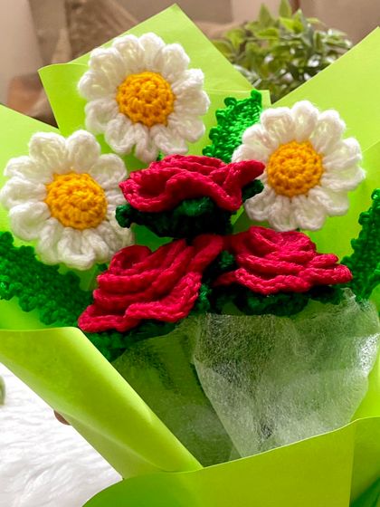 A close-up of the finished bouquet, showing the vibrant red of the crochet roses next to the fresh white of the daisies.