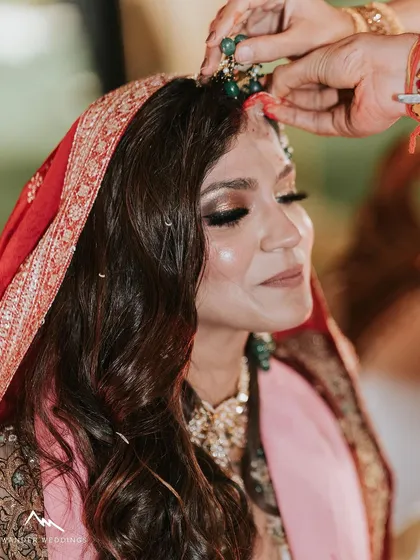 A beautiful candid moment during the ceremony. The close-up shows the shimmering eye makeup and the bride's serene expression.
