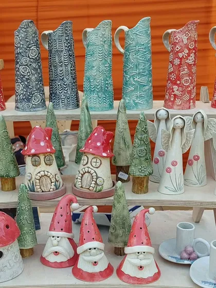 A beautiful display of my Christmas collection at a potter's market, featuring textured pitchers, mushroom houses, gnomes, and angel figurines.