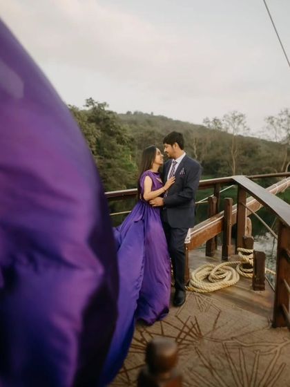 A rich purple gown for a vibrant and unique pre-wedding photo. The flowing trail adds a touch of magic to this romantic moment on a wooden deck.