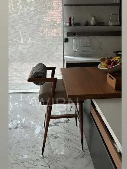 Another view of the custom barstool, showing the comfortable leather seat and the unique cylindrical backrest in a patterned fabric.