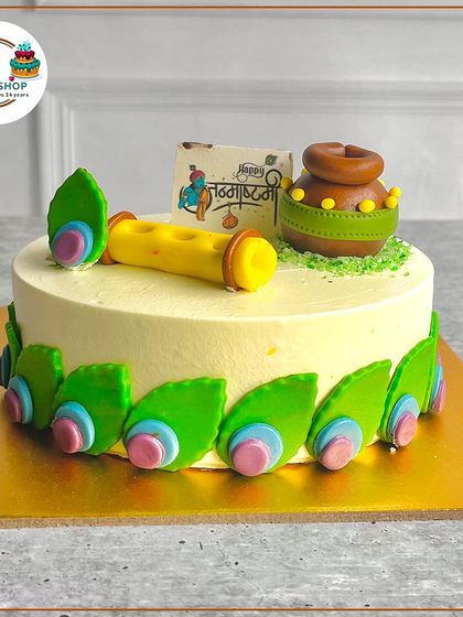 Our Janmashtami cake featuring a handcrafted fondant flute and 'dahi handi' pot, surrounded by peacock feather-inspired decorations.