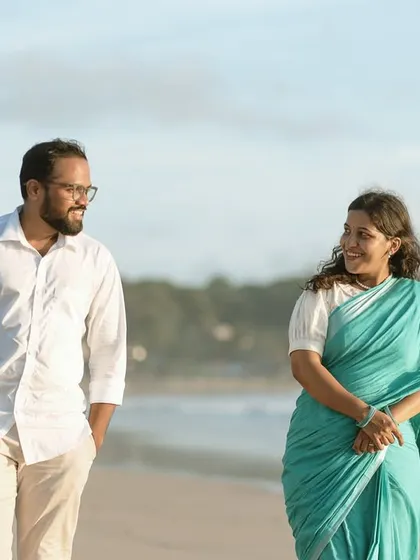 A candid moment of conversation and smiles between the couple as they stroll along the shoreline, with the ocean waves in the background.