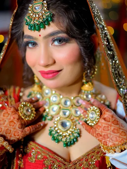 A close-up bridal shot with a bright, happy expression, focusing on the colorful jewelry and makeup.